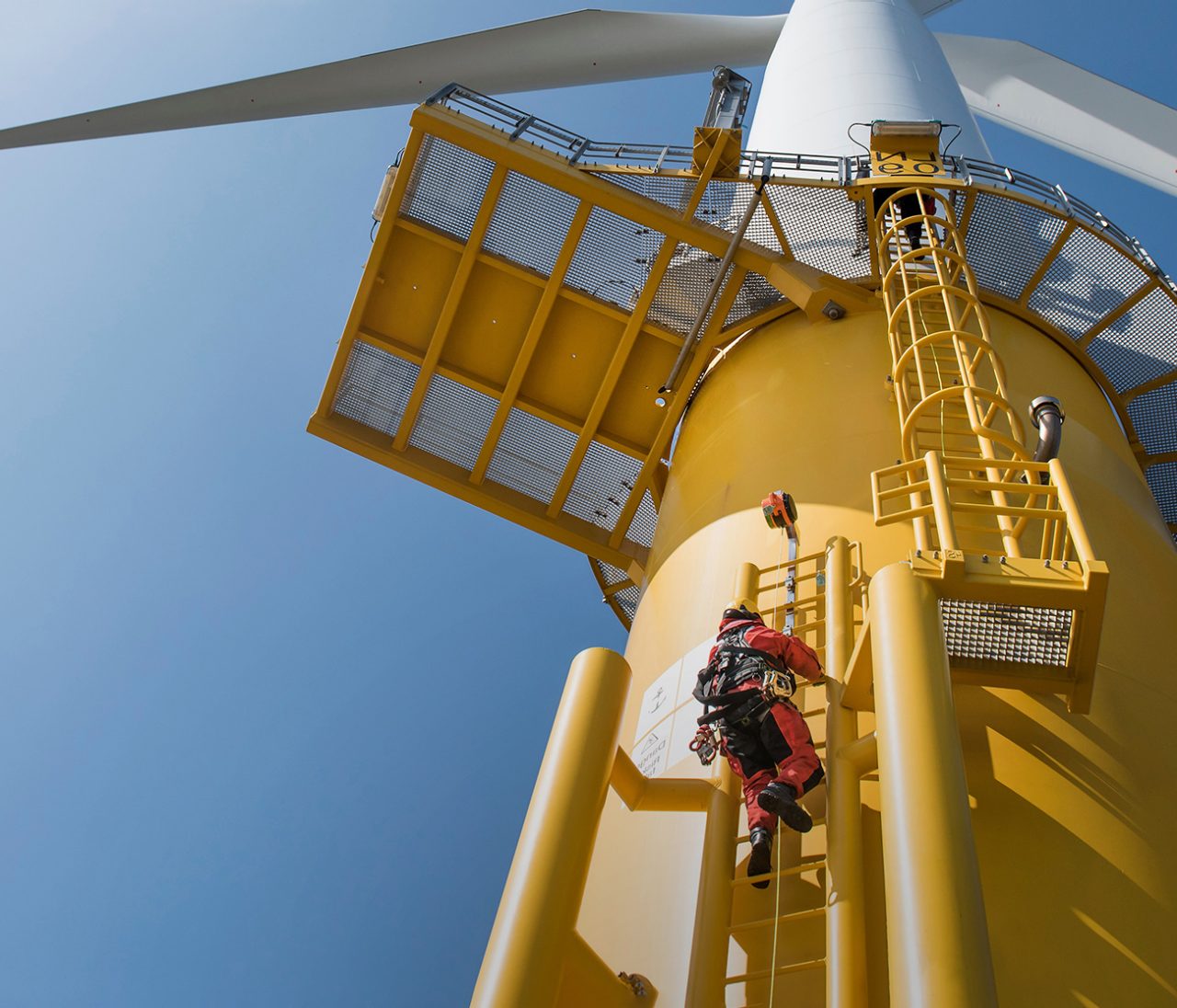Worker climbing a wind turbine on the outside
