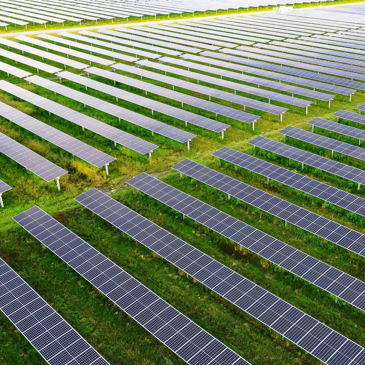 Ground-mounted solar panels seen from the air stretching into distance on green grass