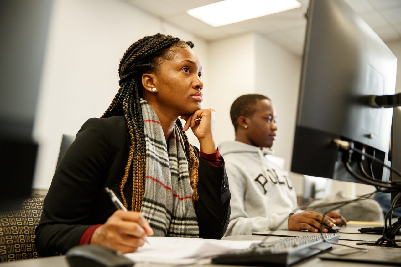 Two people working at a computer screen