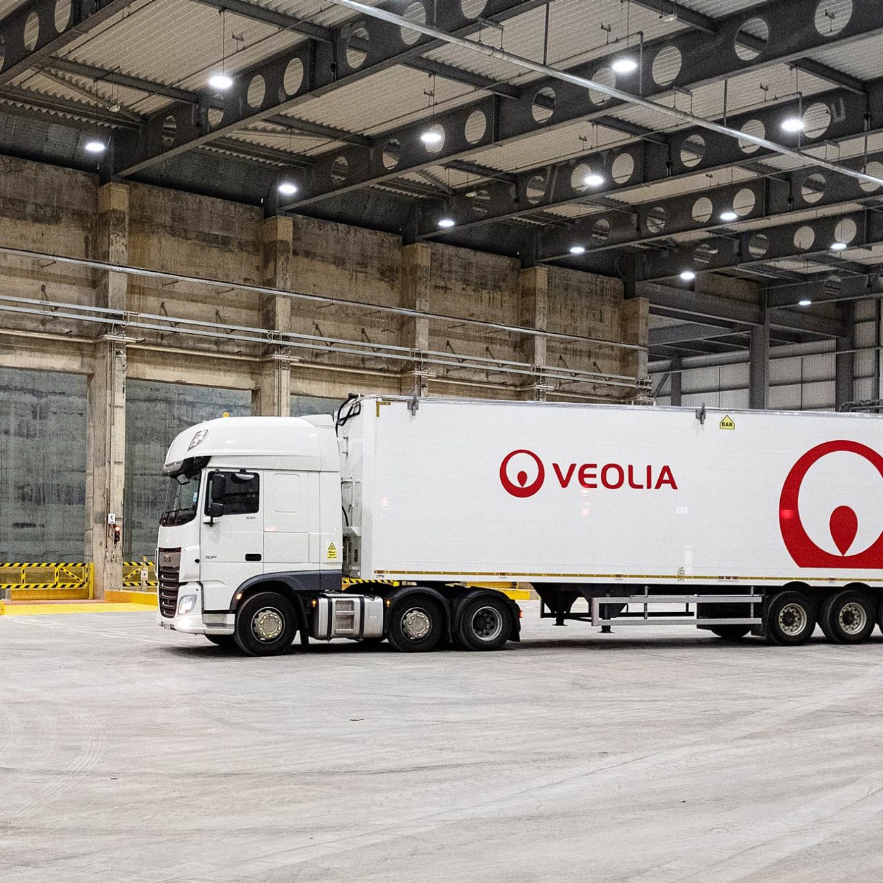 White lorry with red Veolia logo in large industrial space