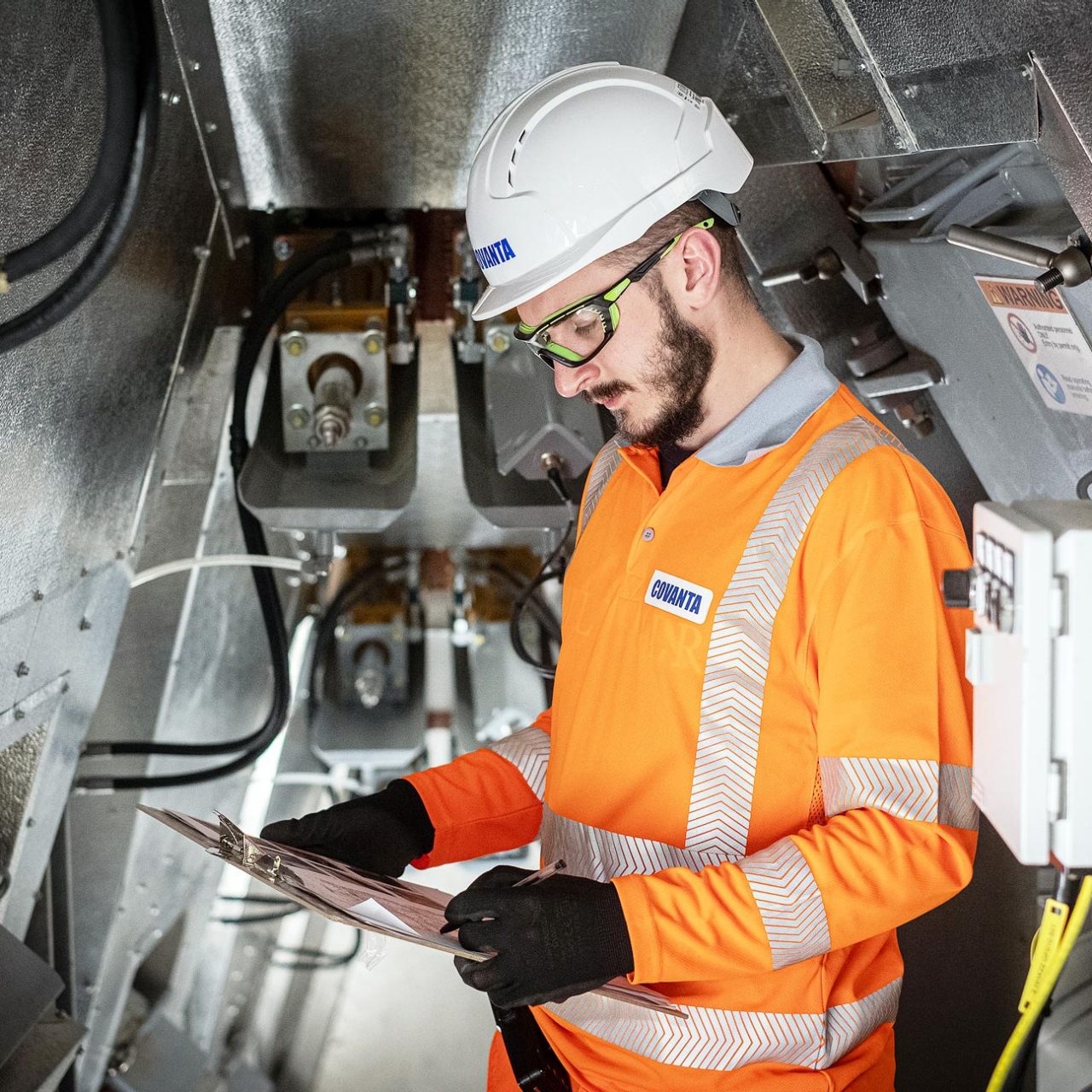 Man in PPE looking at clipboard