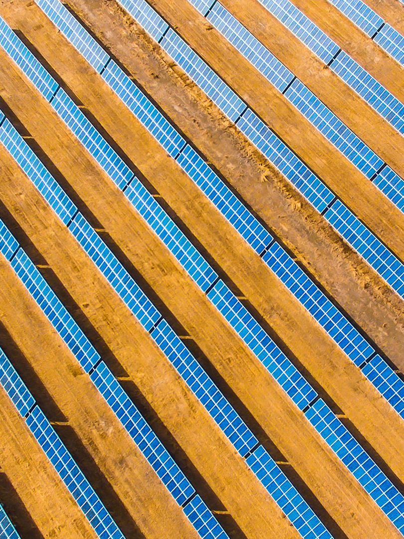 Rows of blue solar panels on orange dirt