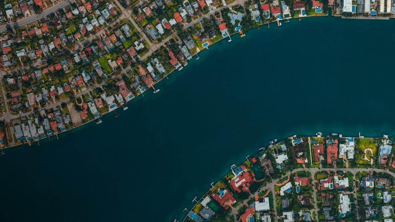 Aerial view of blue river flowing through houses on either side