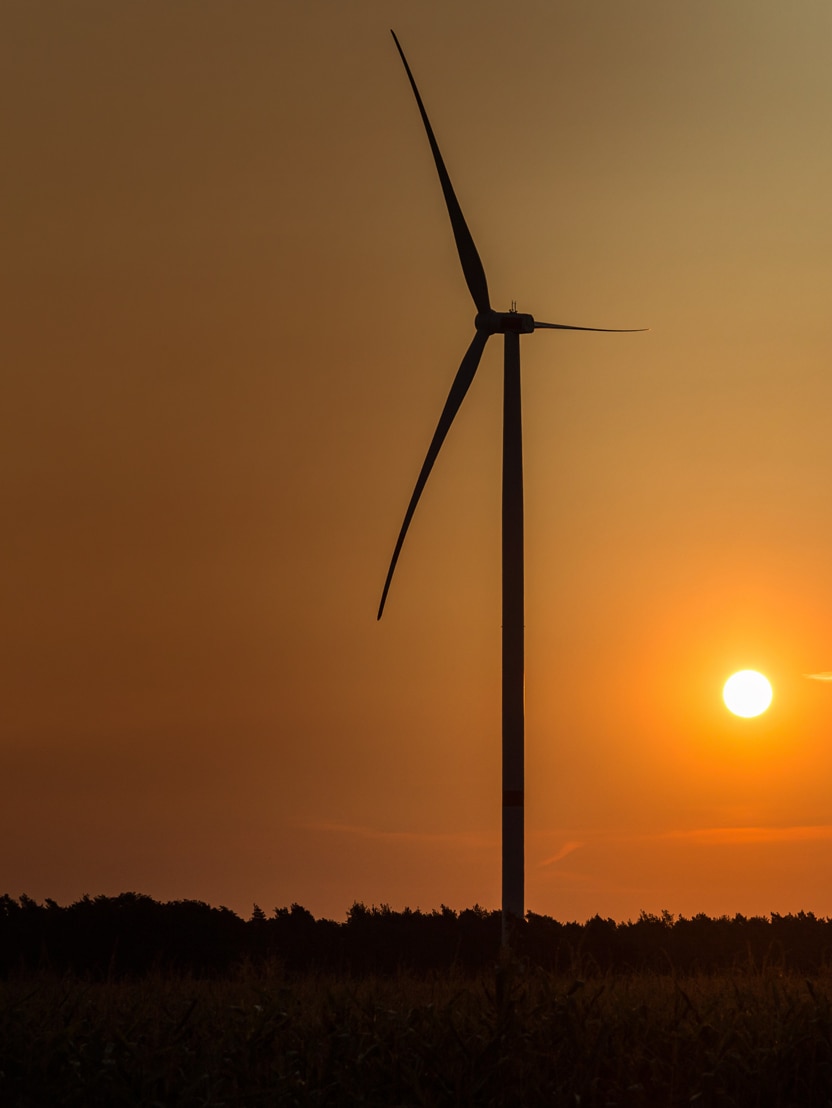 Single wind turbine in front of orange sunset