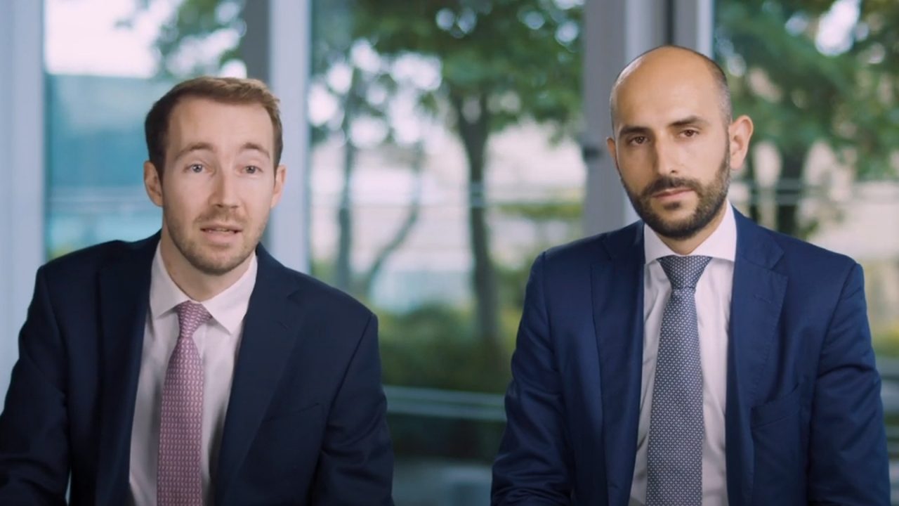 Two men in suits and ties looking into a camera