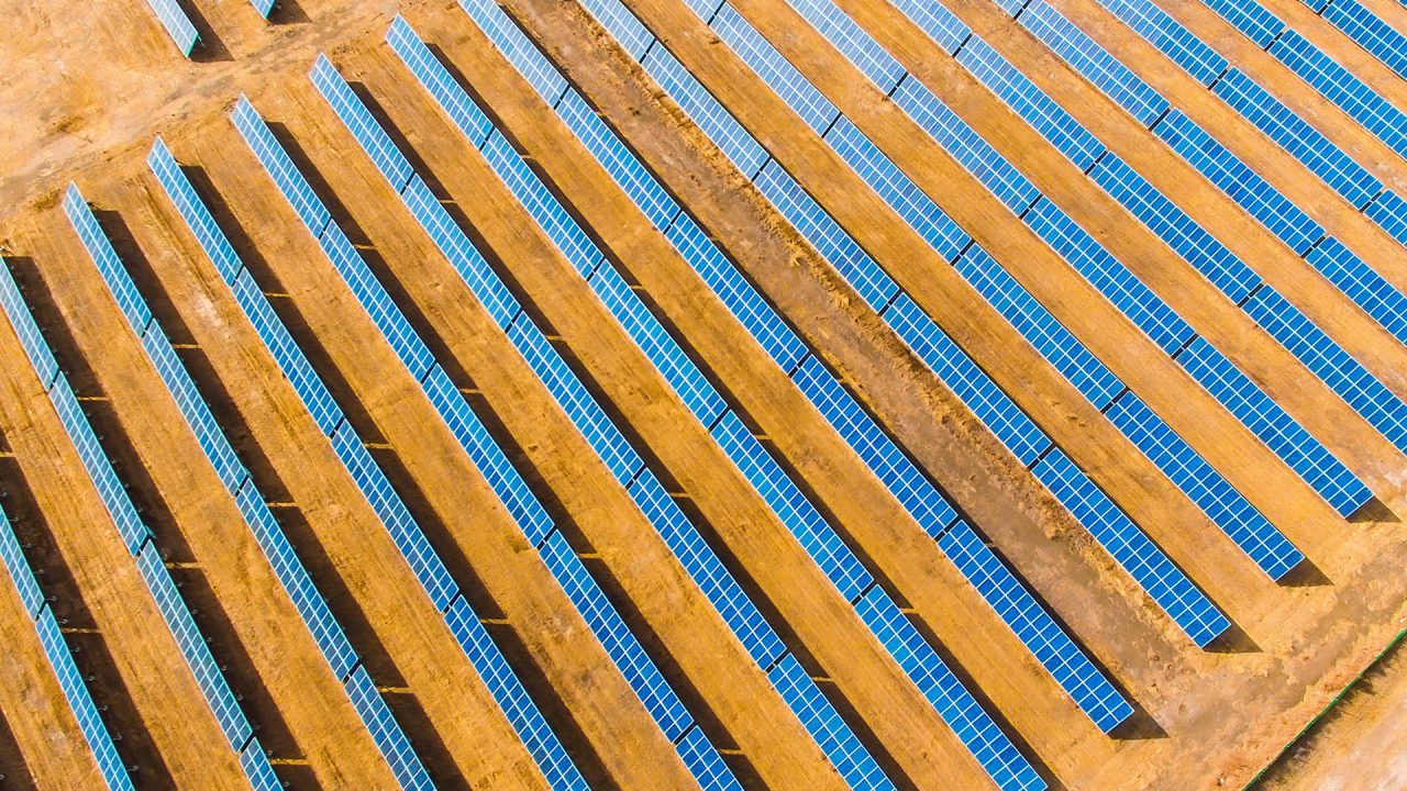 Rows of blue solar panels on orange dirt