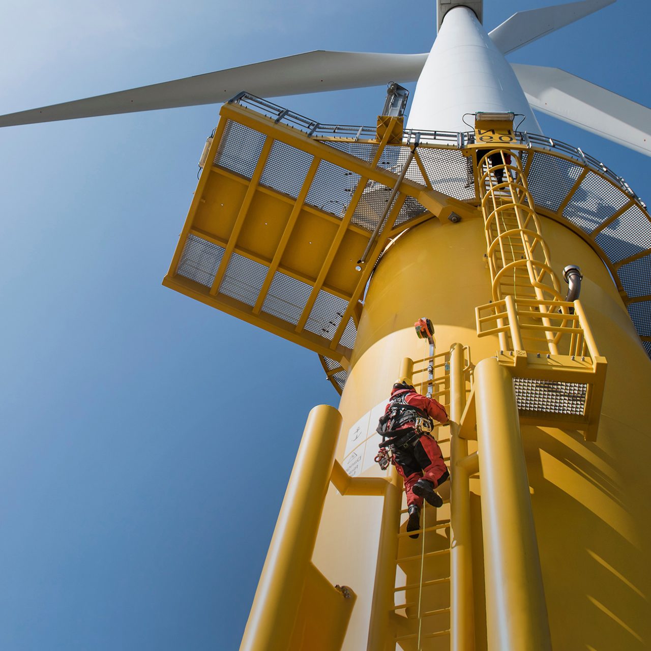 Worker climbing wind turbine via outside ladder