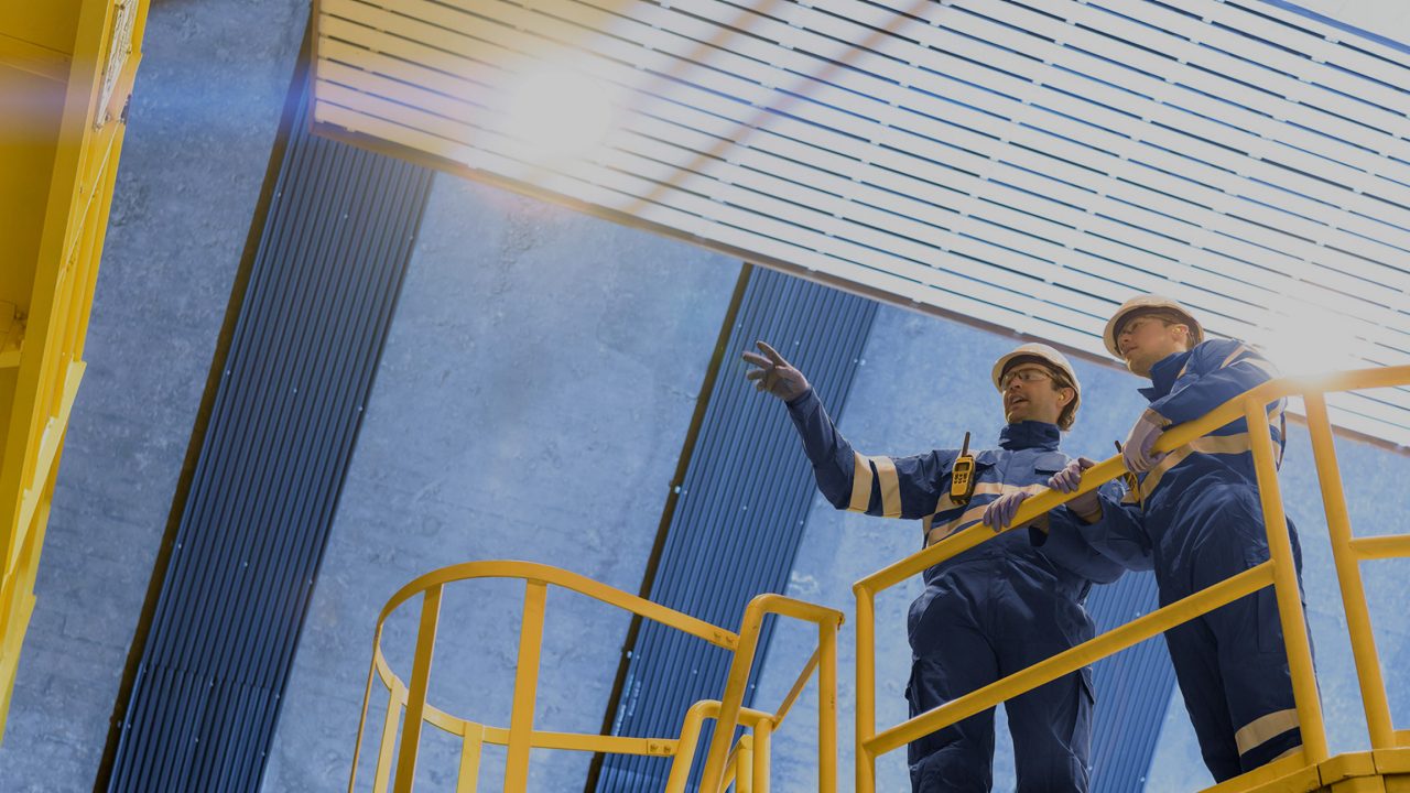 Two workers in hard hats on a yellow platform