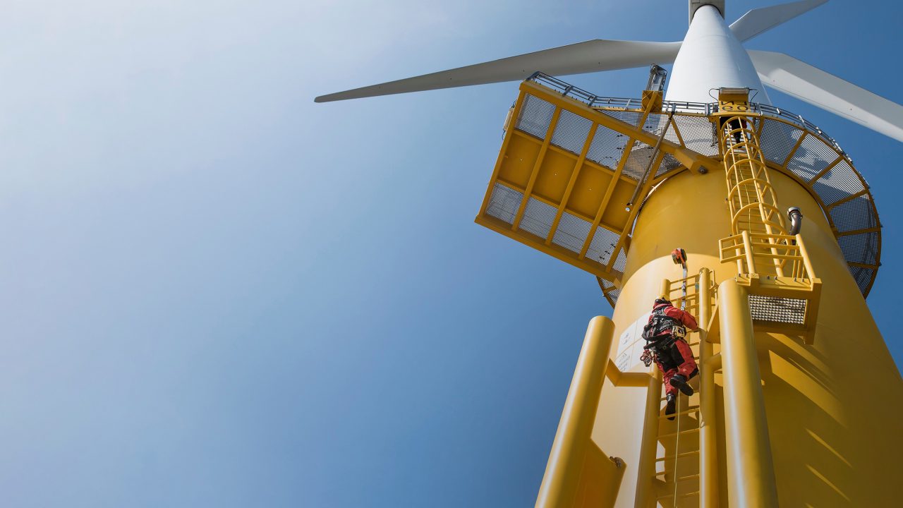 Worker climbing the outside of a wind turbine on the outside